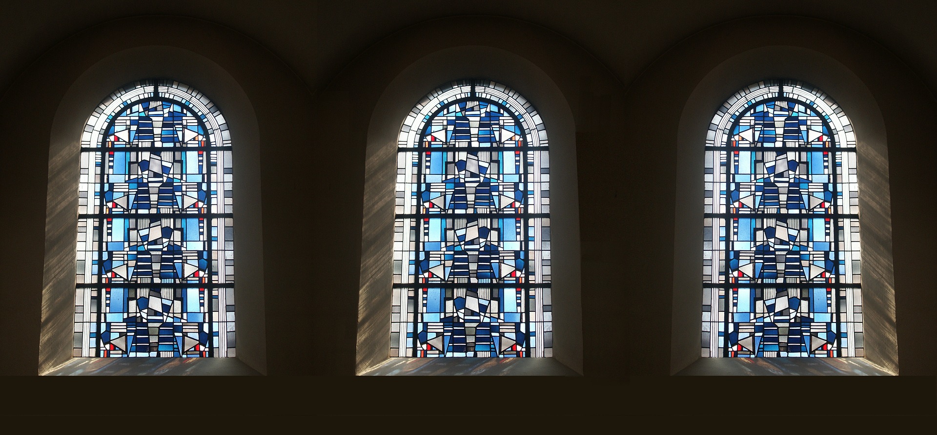 This image displays blue stained glass, in three arched windows.
